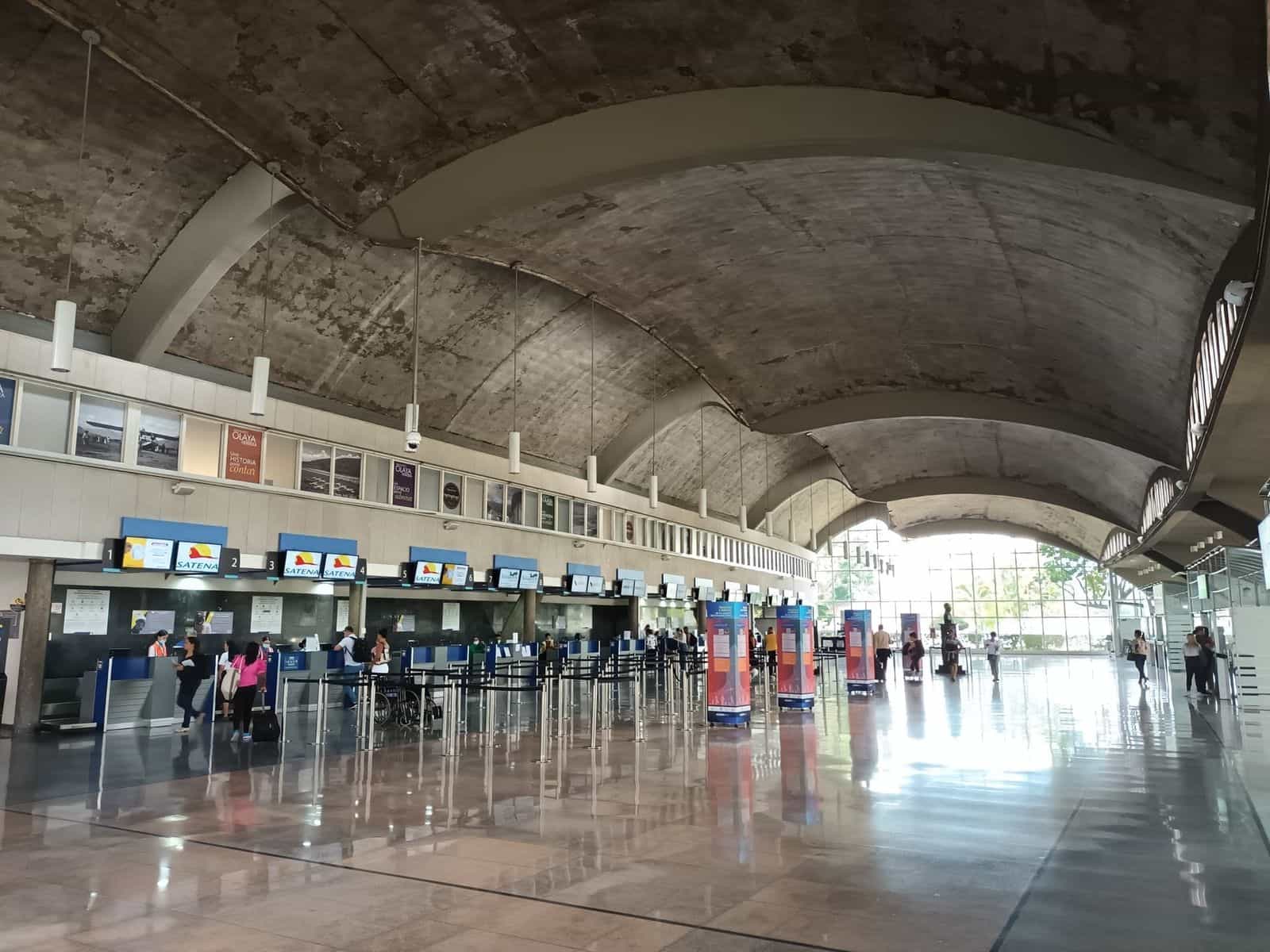 Innenansicht des Flughafens Olaya Herrera: Haupthalle mit Schaltern regionaler Airlines, hängender Beschilderung und Passagieren auf dem Weg zum Boarding