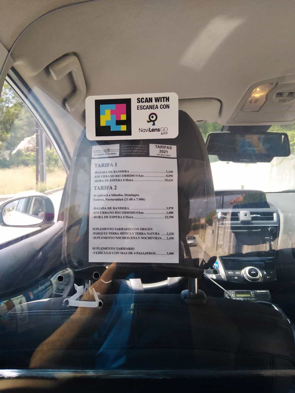 Plano vertical del panel de tarifas 2021 del Ajuntament de Benidorm con el cartel superior NaviLens GO dentro del taxi.