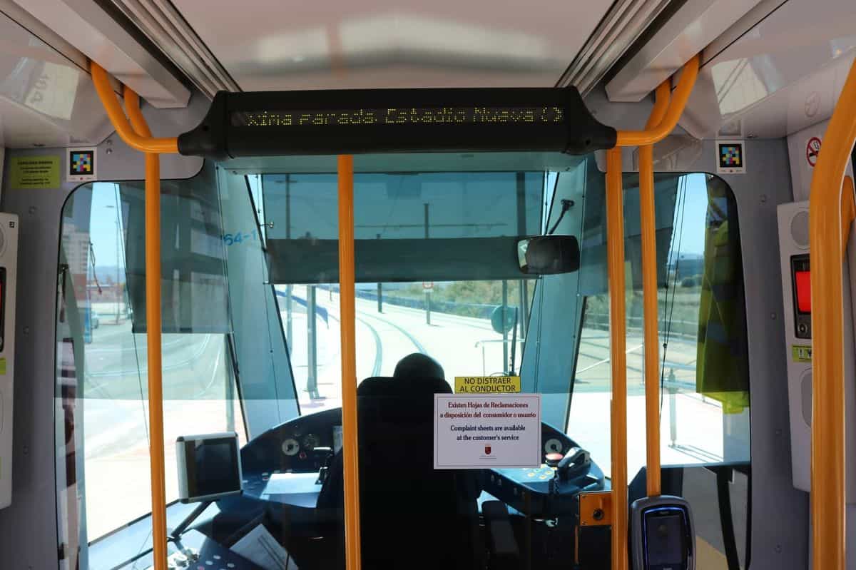 Persona escaneando un código NaviLens situado en lo alto de una marquesina del Tranvía de Murcia, con la pantalla LED de próximas llegadas al fondo