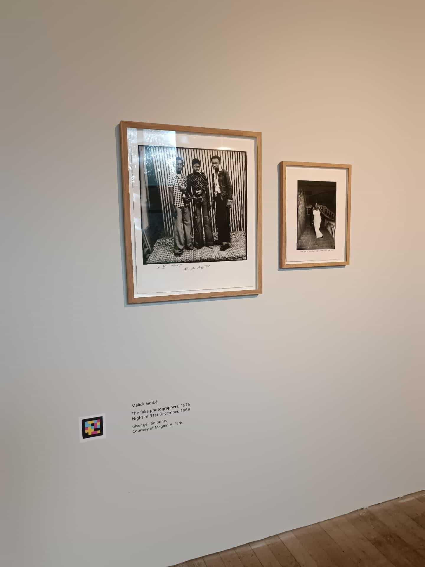 Malick Sidibé artwork caption (The fake photographers, 1976 and Night of 31st December, 1969, silver gelatin prints) with a NaviLens code next to it, under two framed photographs