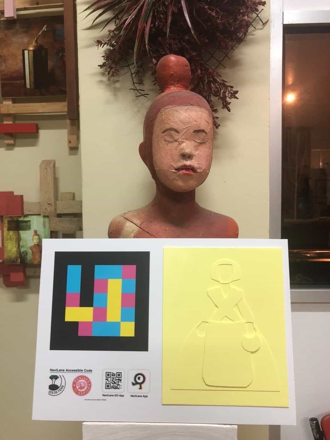 Panel del proyecto con código NaviLens y relieve amarillo de una Menina sosteniendo una jarra, con los logos de IES de Fene, Meninas de Canido y NaviLens GO al pie del cartel