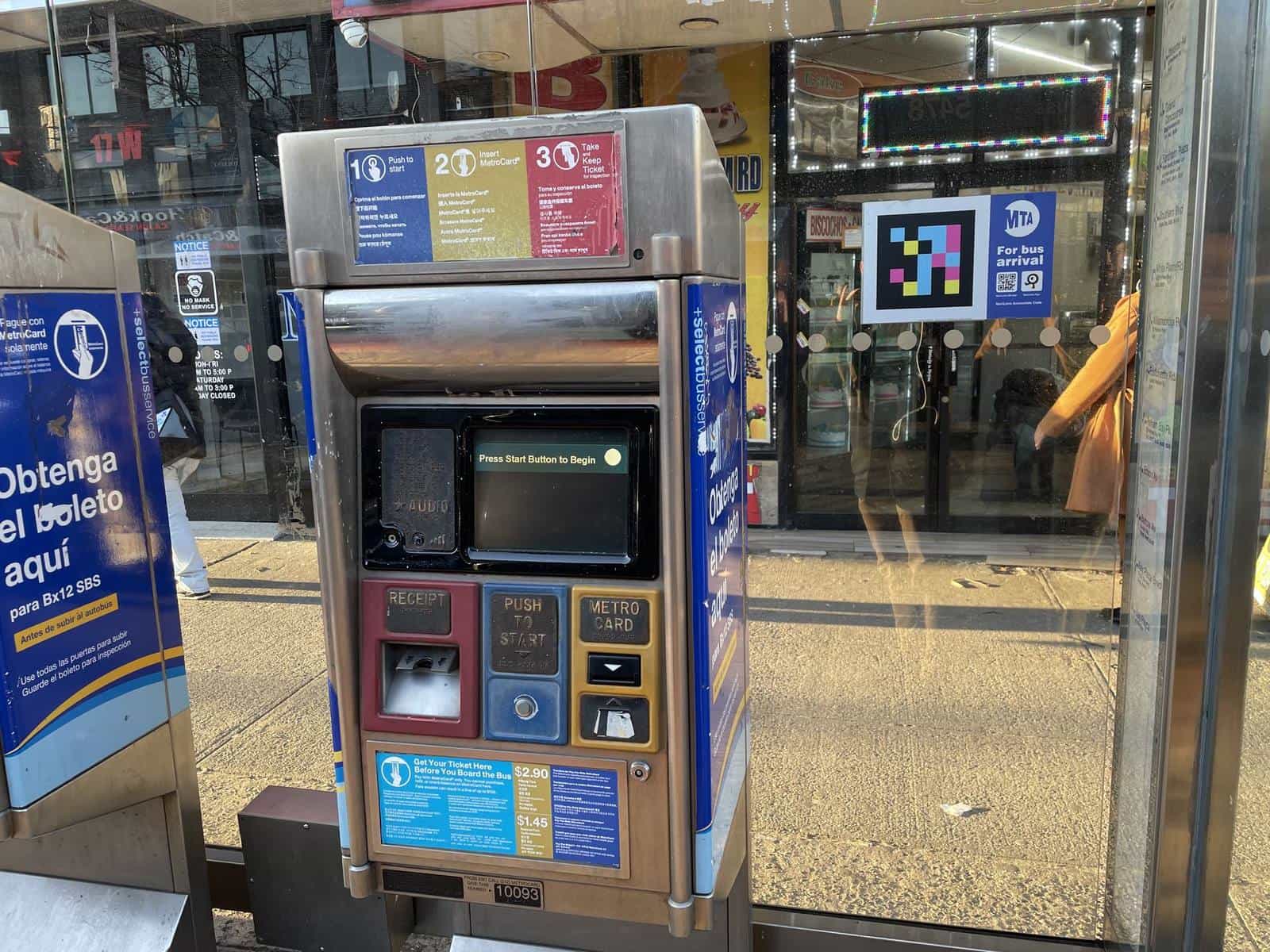 Bx12 SBS prepay machine on the pavement, with the “Obtenga el boleto aquí” sign and a NaviLens code next to the shelter’s “For bus arrival” panel