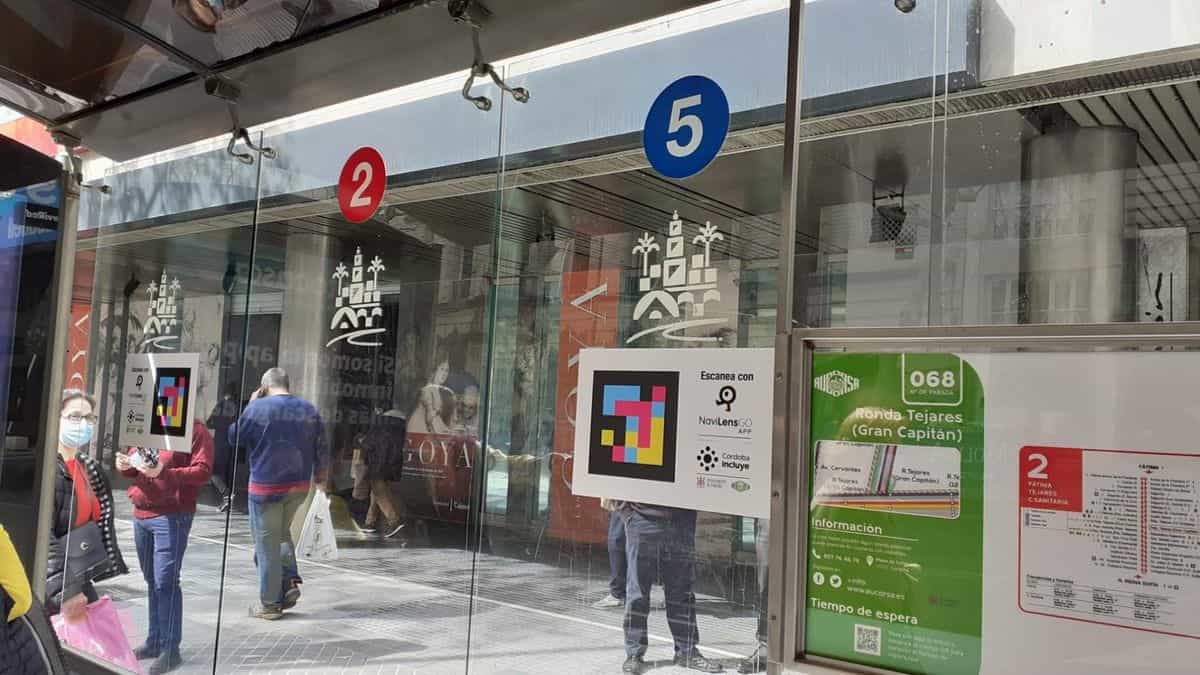 Marquesina del bus urbano de AUCORSA en Ronda de Tejares (Córdoba): líneas 2 y 5, código NaviLens junto al cartel «Escanea con NaviLensGO · Córdoba Incluye»