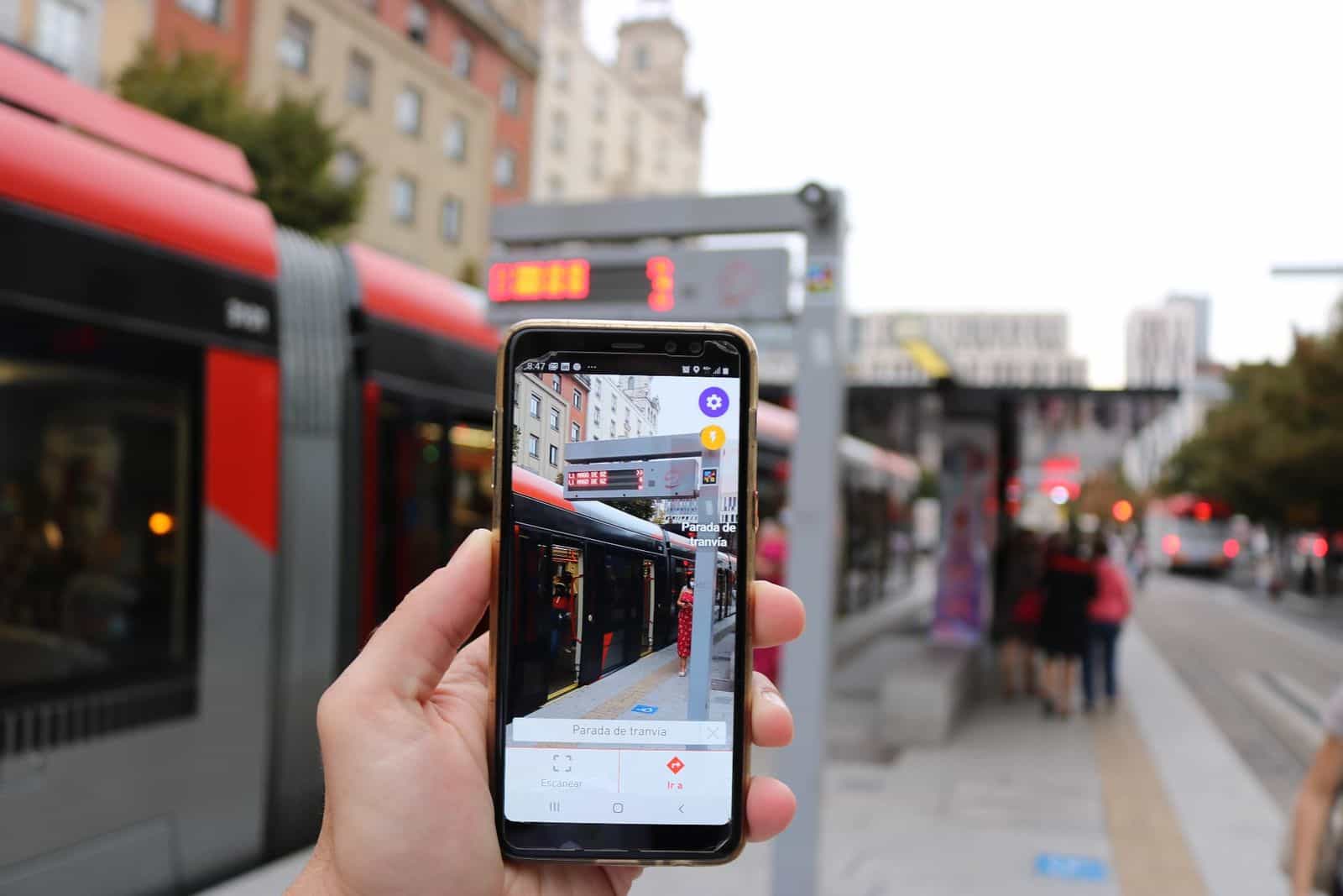 Telefono che mostra l’app NaviLens mentre legge la fermata del tram di Saragozza con un Urbos rosso sullo sfondo