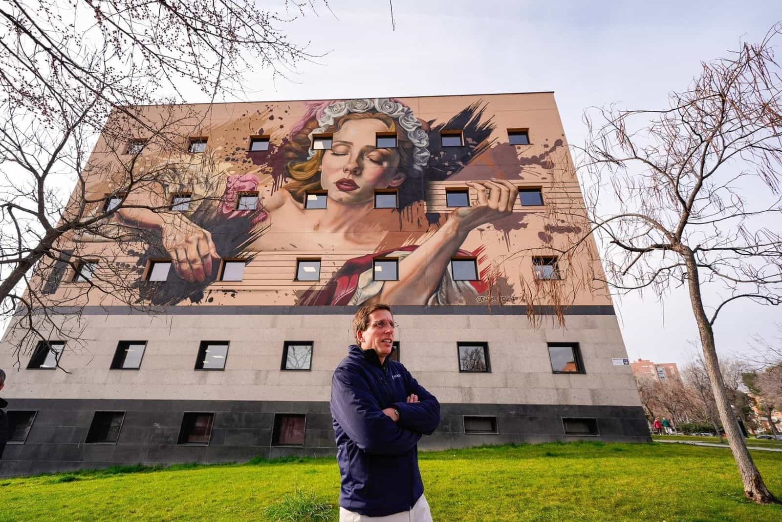 Murale di SFHIR sulla facciata di un edificio comunale di Moratalaz: giovane donna con corona di rose bianche su fondo sabbia, che occupa sei piani.