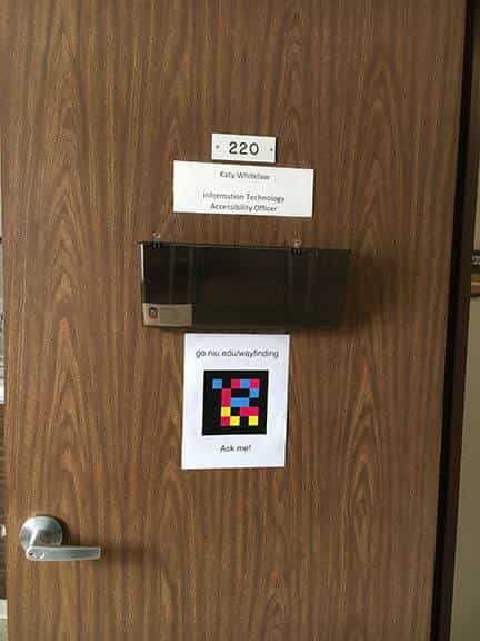 Door to Katy Whitelaw's office 220, IT Accessibility Officer at NIU, with a "Ask me!" NaviLens code and the URL go.niu.edu/wayfinding