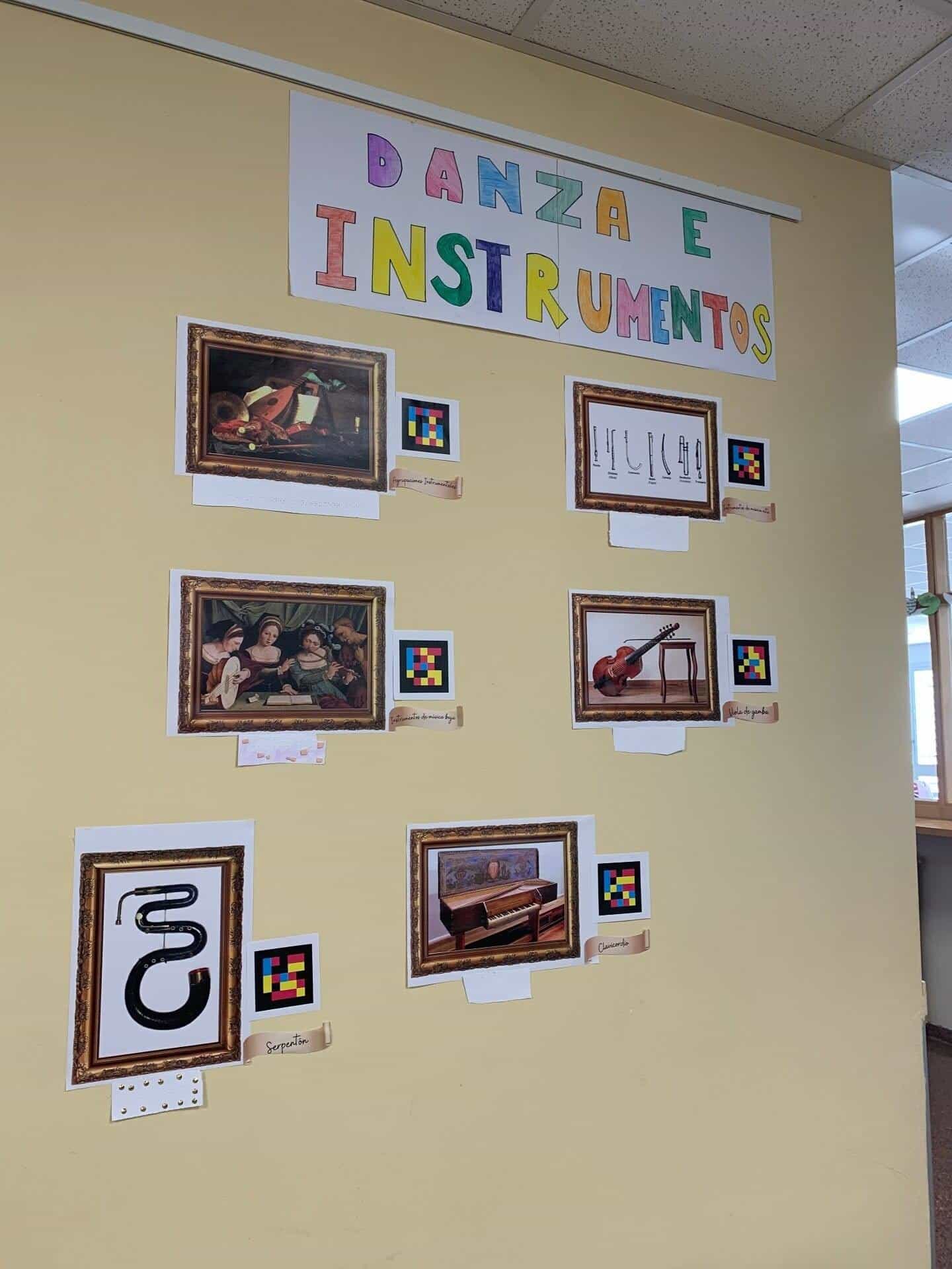 Panel «Danza e Instrumentos» with six framed pictures —instrumental groups, high and low music instruments, viola da gamba, serpent and clavichord— each with its NaviLens code and label, in the museum of IES Clara Campoamor