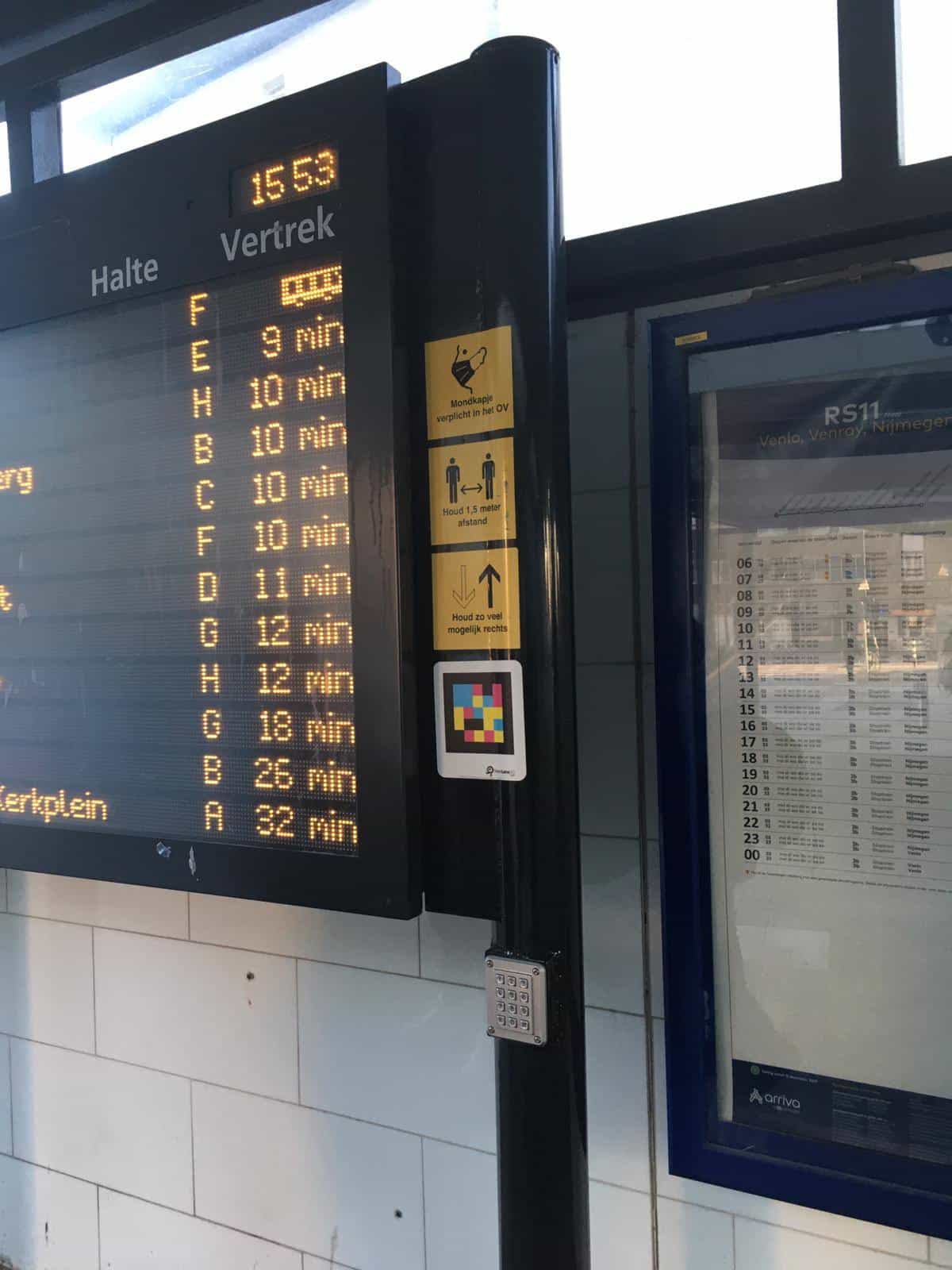 Halte/Vertrek departure board at Roermond bus station next to a NaviLens code and the printed schedule of Arriva line RS11 to Venlo, Venray and Nijmegen