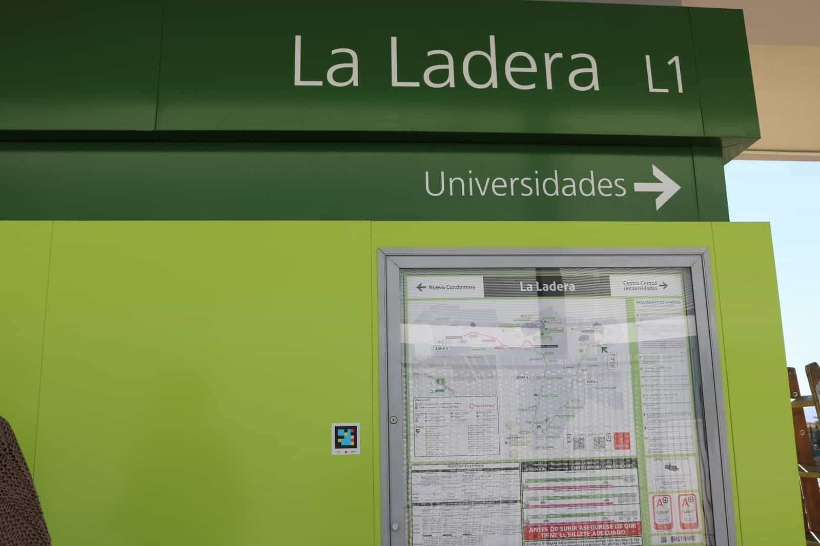 Persona che inquadra un codice NaviLens collocato in cima a una pensilina del Tranvía de Murcia, con lo schermo LED dei prossimi arrivi in fondo