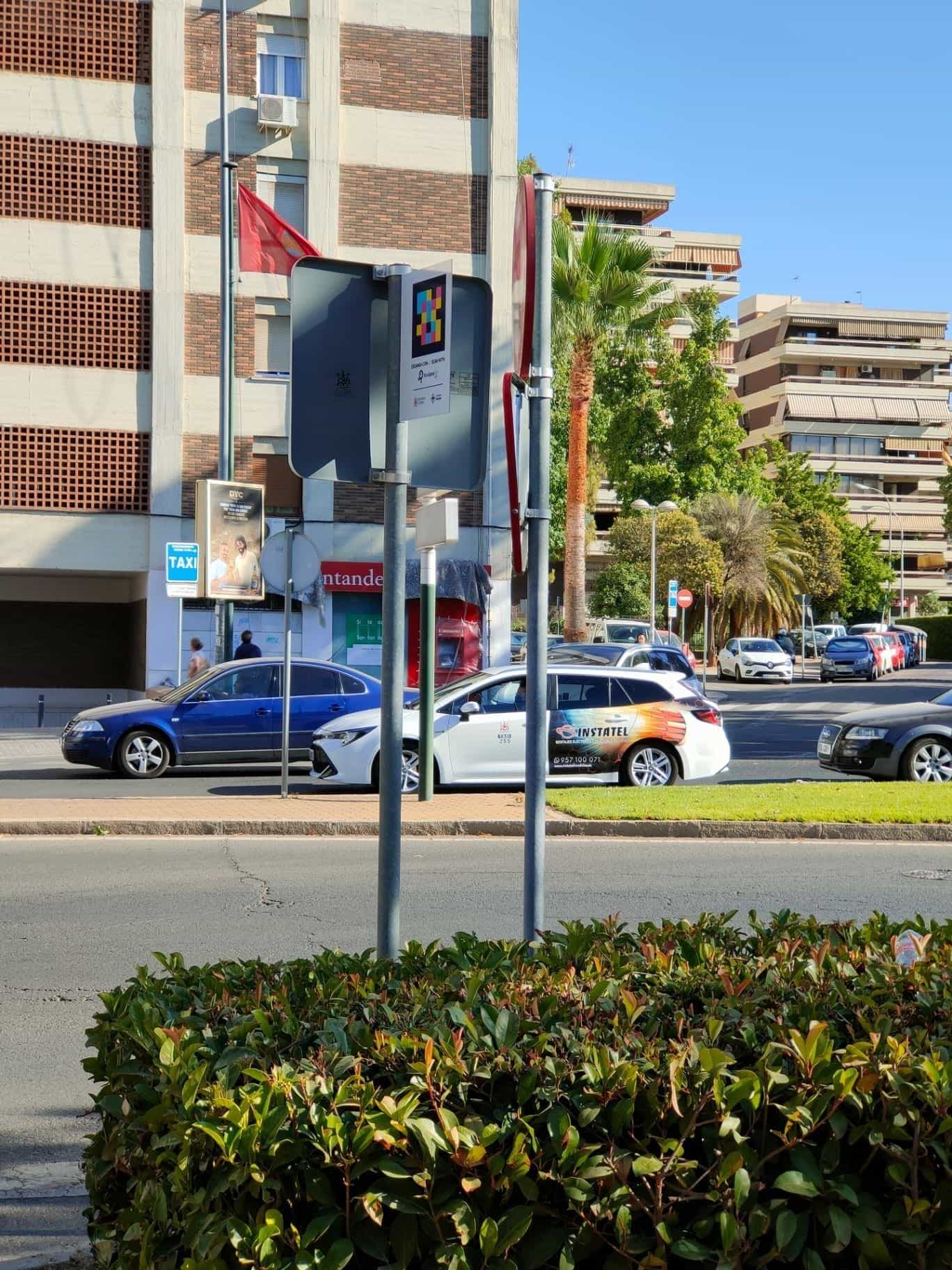 Parada de taxi en una rotonda de Córdoba con cartel NaviLens y un taxi blanco al fondo