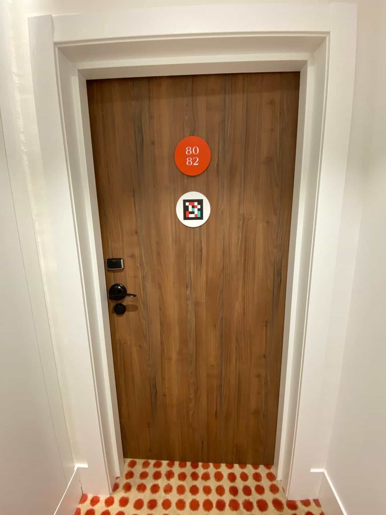 Flur am ibis Styles Sevilla mit benachbarten Zimmern 75 und 73, jeweils mit rotem Nummern-Disc und weißem NaviLens-Disc
