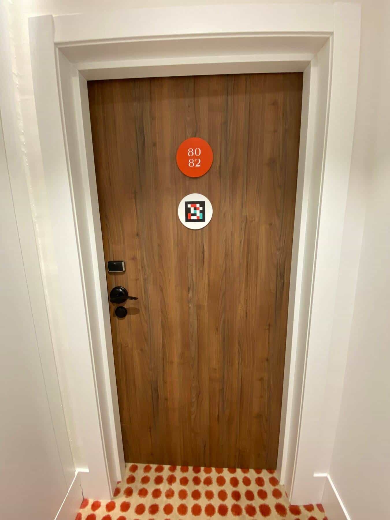 Corridor at ibis Styles Sevilla with adjacent rooms 75 and 73, each with a red numbered disc and a white NaviLens disc