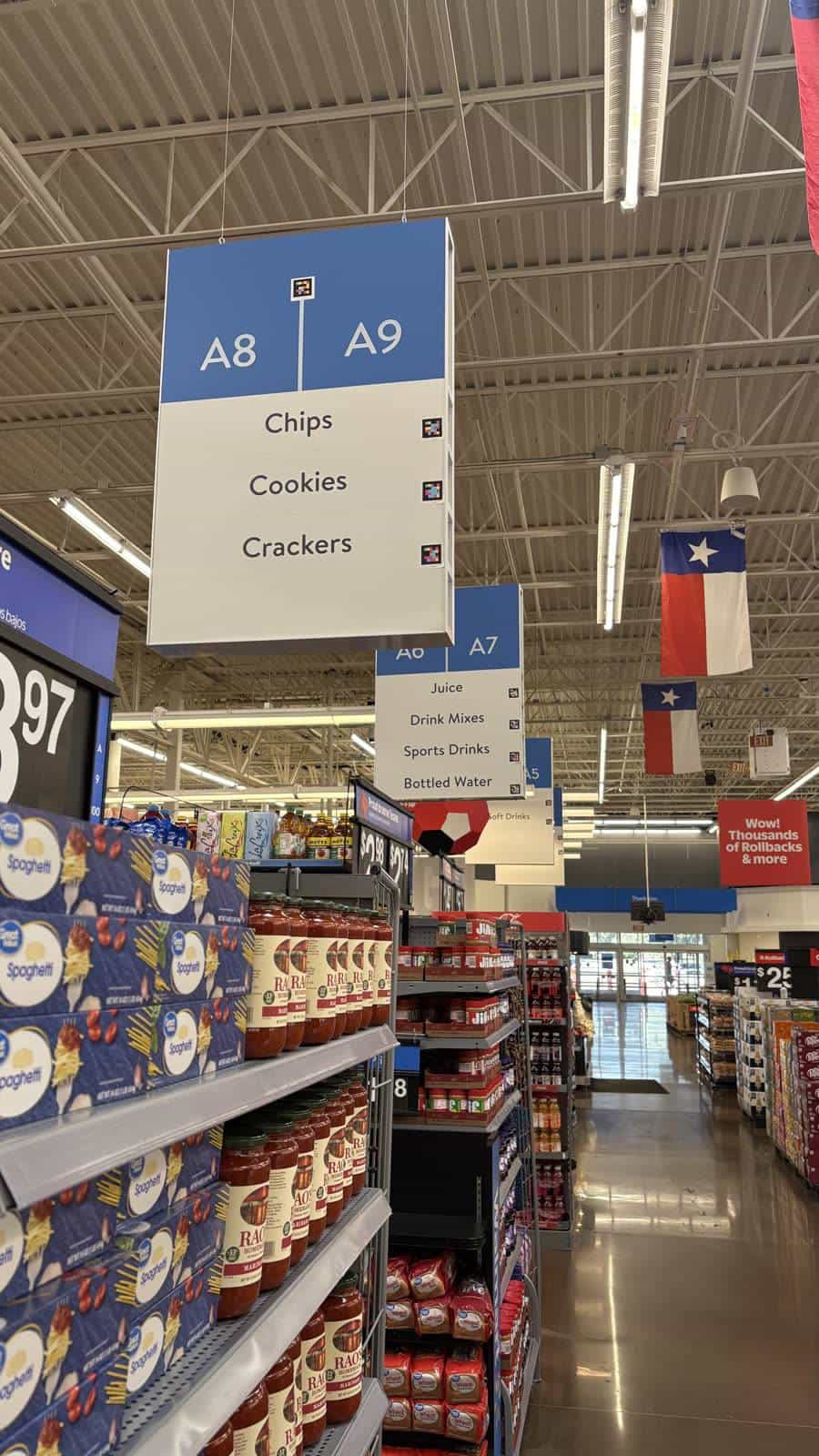 Row of overhead A8·A9, A10·A11 panels with NaviLens codes and Texas flags hanging from the ceiling