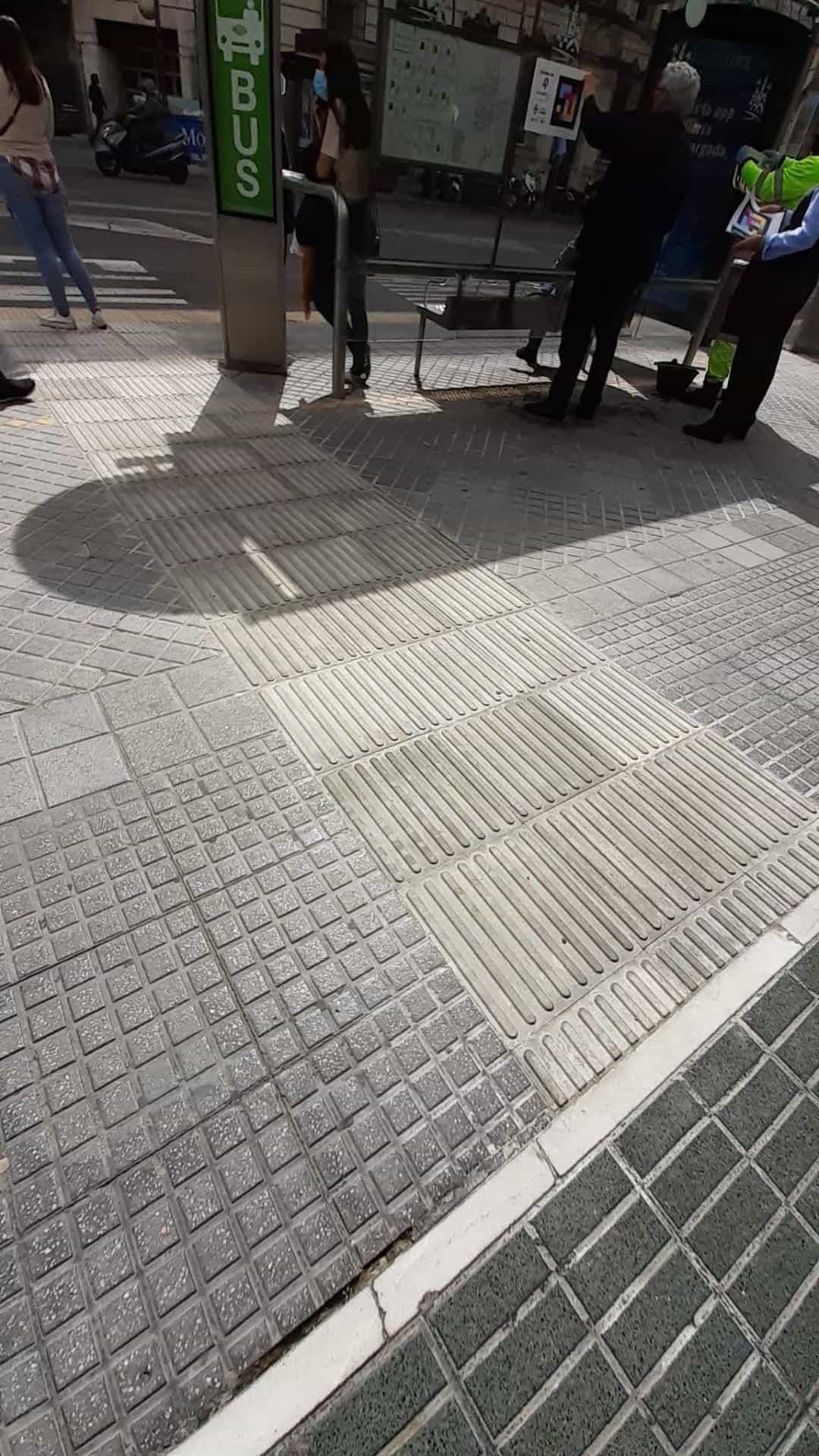 Pavimento podotáctil de encaminamiento que conduce a una marquesina de AUCORSA con cartel NaviLens