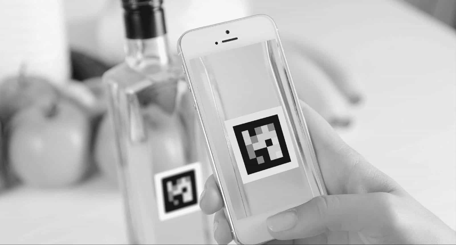 Persona che scansiona con il telefono un codice NaviLens personale applicato su una bottiglia.