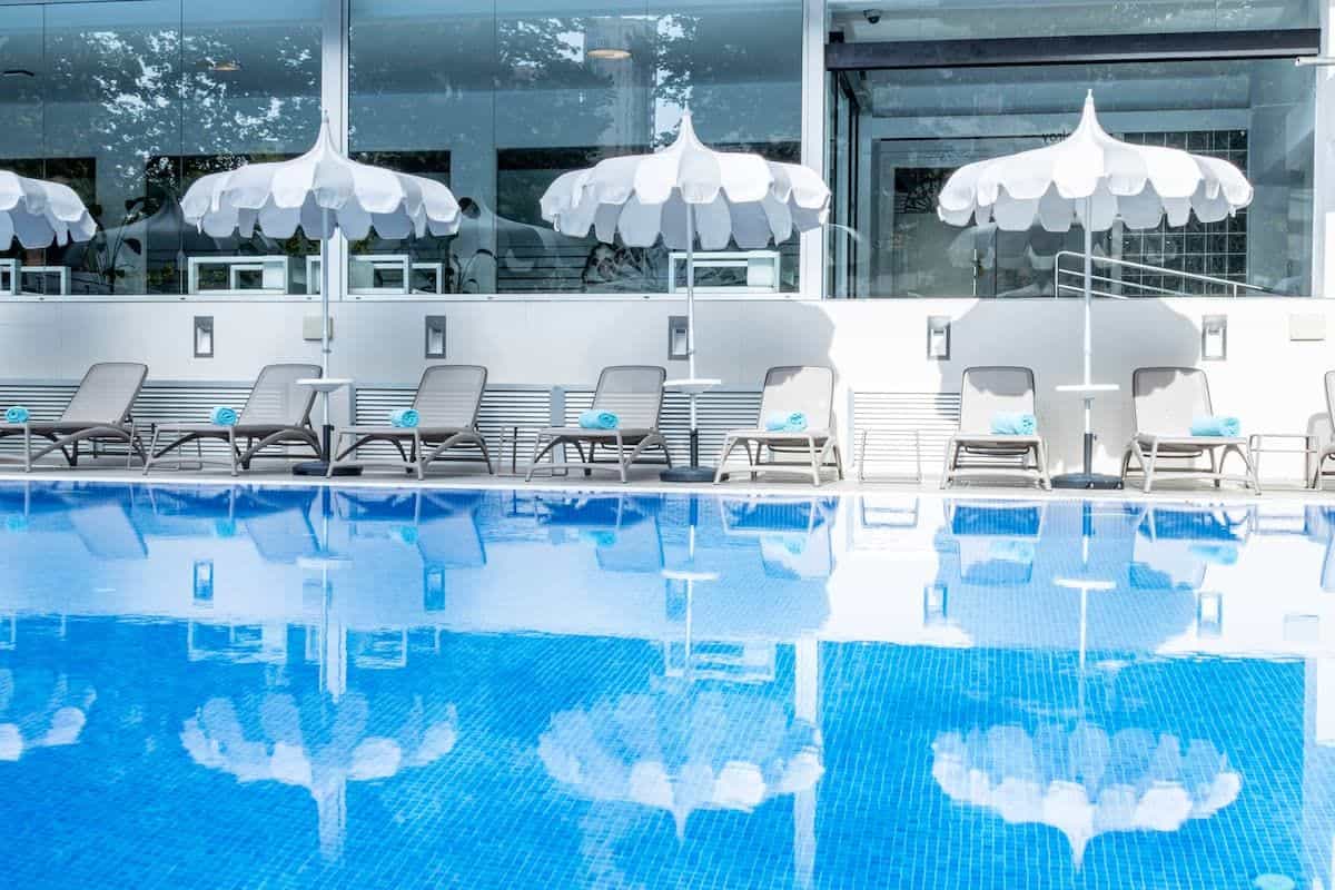 Außenpool im Climia Belroy mit Liegen, Sonnenschirmen und mediterranen Pflanzen rund um die Sonnenterrasse