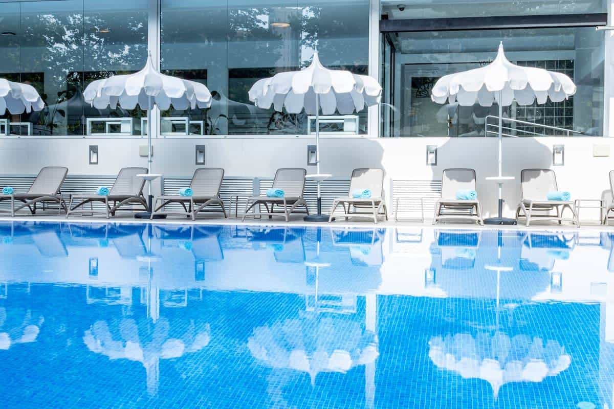 Outdoor pool at the Climia Belroy with sun loungers, parasols and Mediterranean plants around the deck