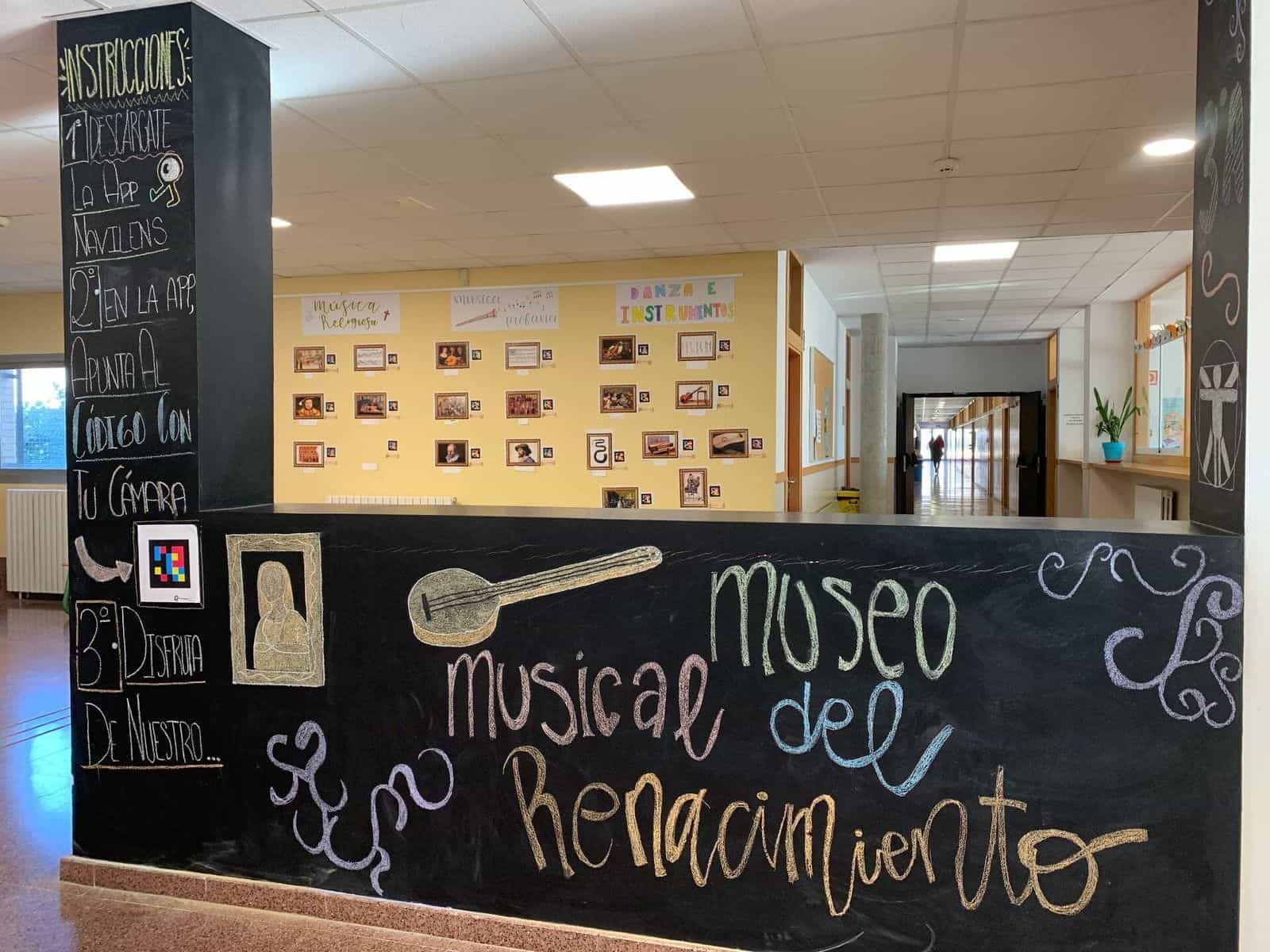 Detail der schiefergrauen Säule im IES Clara Campoamor mit der Anleitung zum Museum: «1.º Descárgate la app NaviLens · 2.º En la app, apunta al código con tu cámara · 3.º Disfruta de nuestro Museo musical del Renacimiento», daneben ein aufgeklebter NaviLens-Code zum Ausprobieren der App