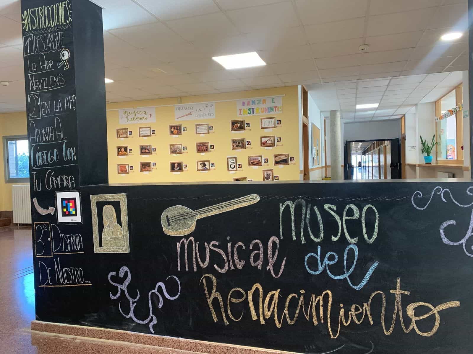 Blick auf den Eingang des Renaissance-Musikinstruments-Museums des IES Clara Campoamor Rodríguez in Zaragoza, mit der Kreidetafel, einem NaviLens-Code und den Tafeln für religiöse, weltliche und Tanzmusik im Hintergrund