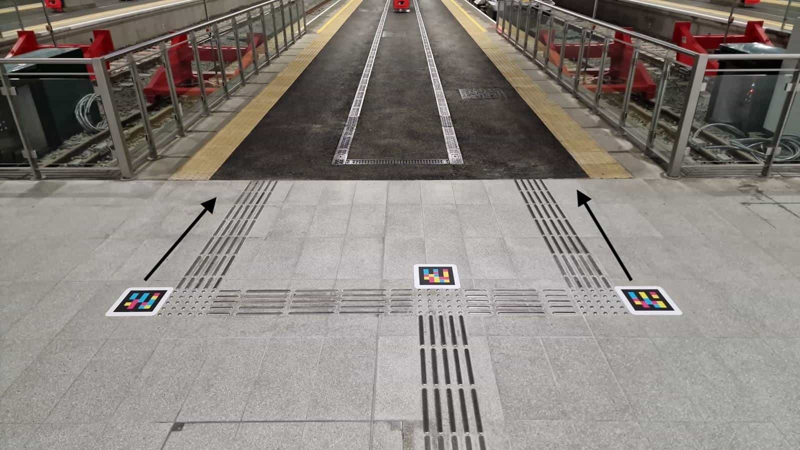 Three NaviLens codes at a tactile-guidance junction on a Belfast Grand Central Station platform