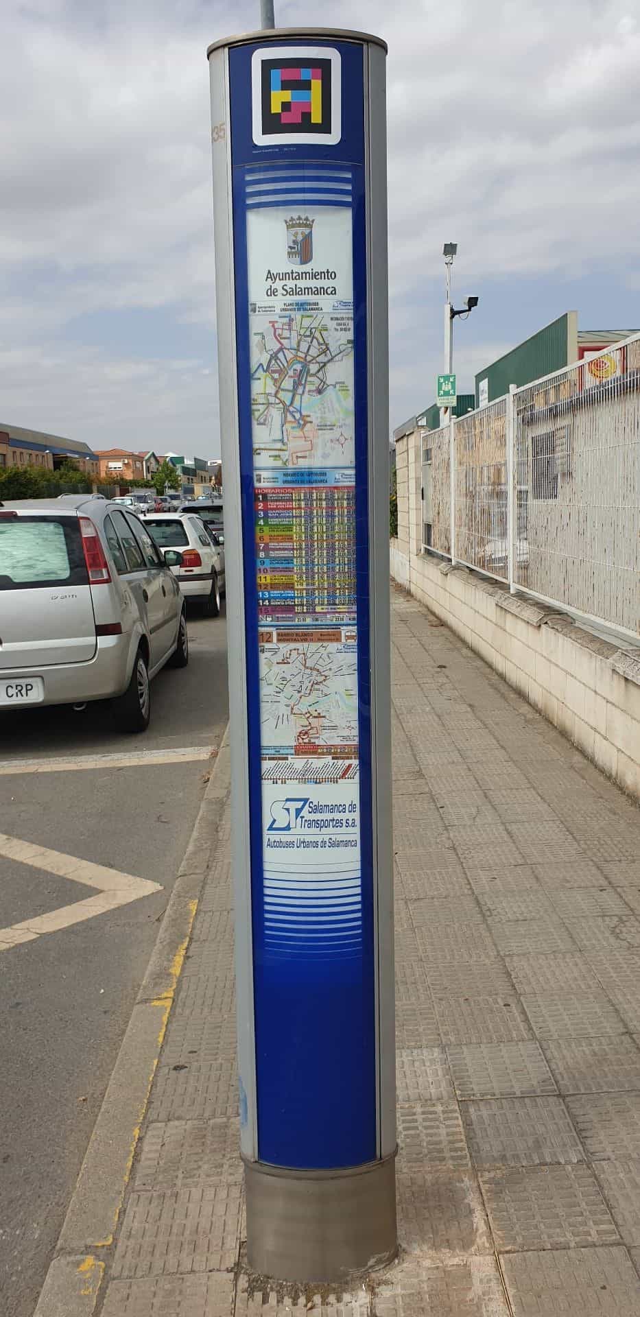 Poste vertical azul de parada del autobús urbano de Salamanca con el código NaviLens en la cabecera y el plano y horarios del Ayuntamiento de Salamanca y Salamanca de Transportes debajo