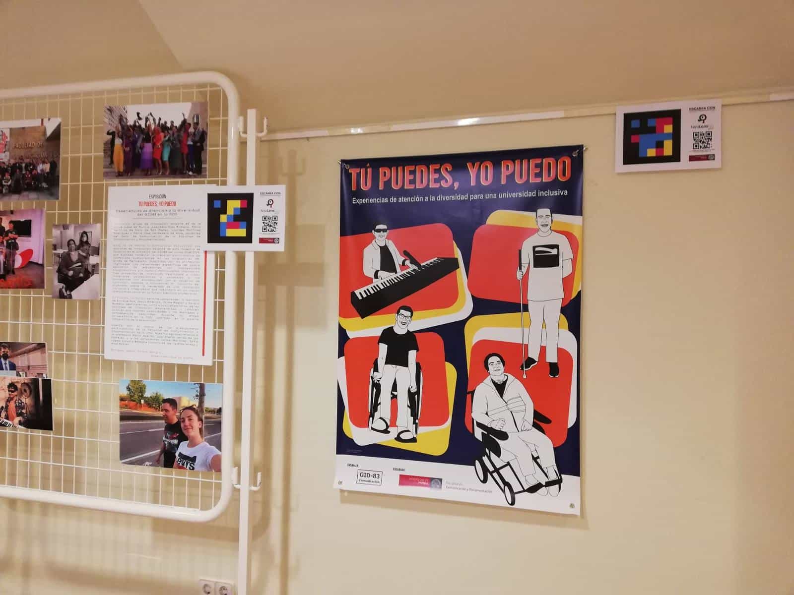 View of the “You can, I can” exhibition in a corridor of the University of Murcia's School of Communication: official poster with four illustrated portraits and, above it, a white card with the NaviLens code and the prompt “SCAN WITH NaviLensGO”