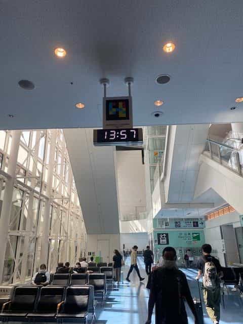 Digitaluhr «Departures 13:57» von der Decke hängend neben einem NaviLens-Code