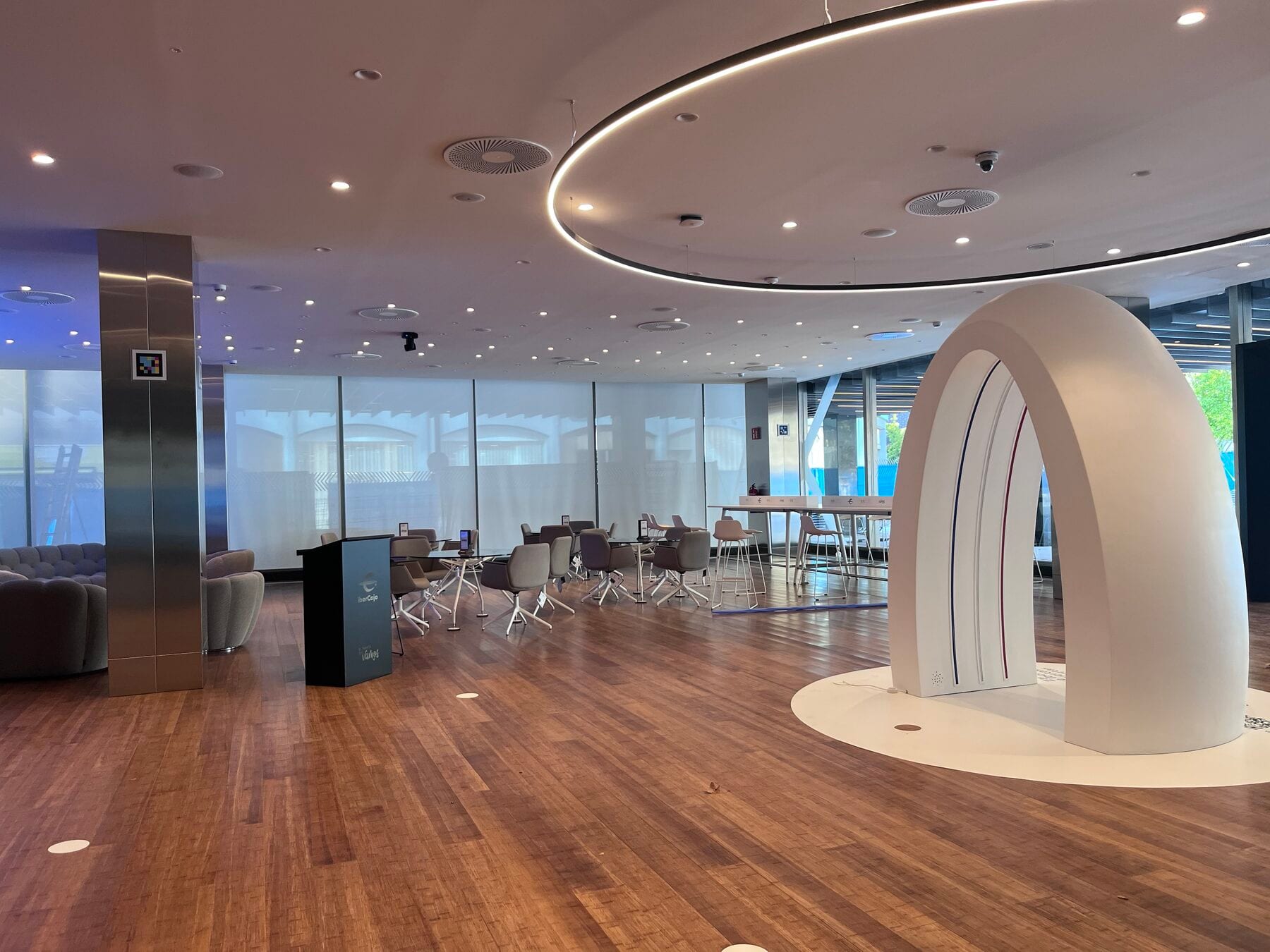 Sala circular del Espacio Xplora con el arco blanco de la Zona Xperiencia y un código NaviLens en la columna de acero