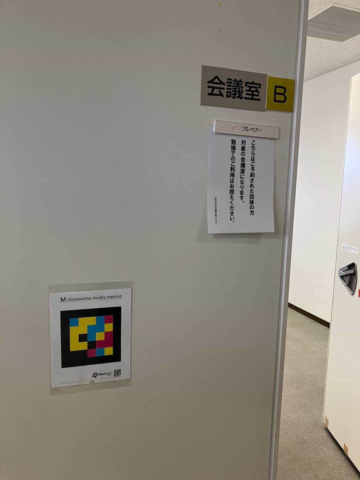 Meeting Room B (会議室 B) at the Yamagata City Civic Activity Support Center with an accessible NaviLens code beside the door