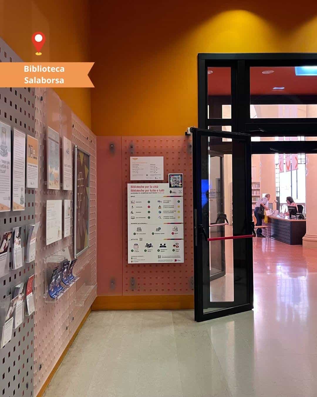 Entrance of Biblioteca Salaborsa in Bologna with the accessibility panel and NaviLens NAQR code next to the door