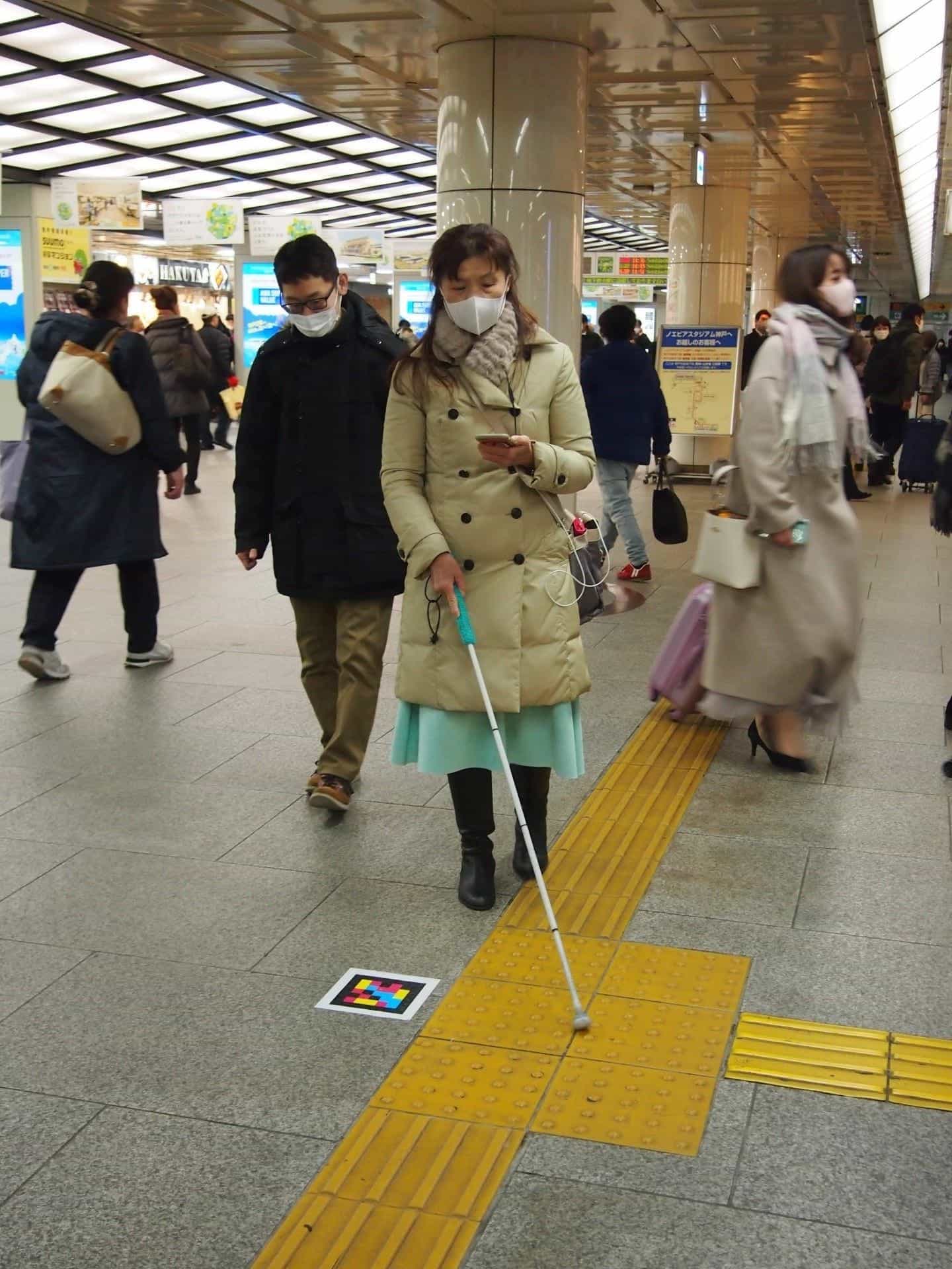 NaviLens user at Sannomiya station with white cane