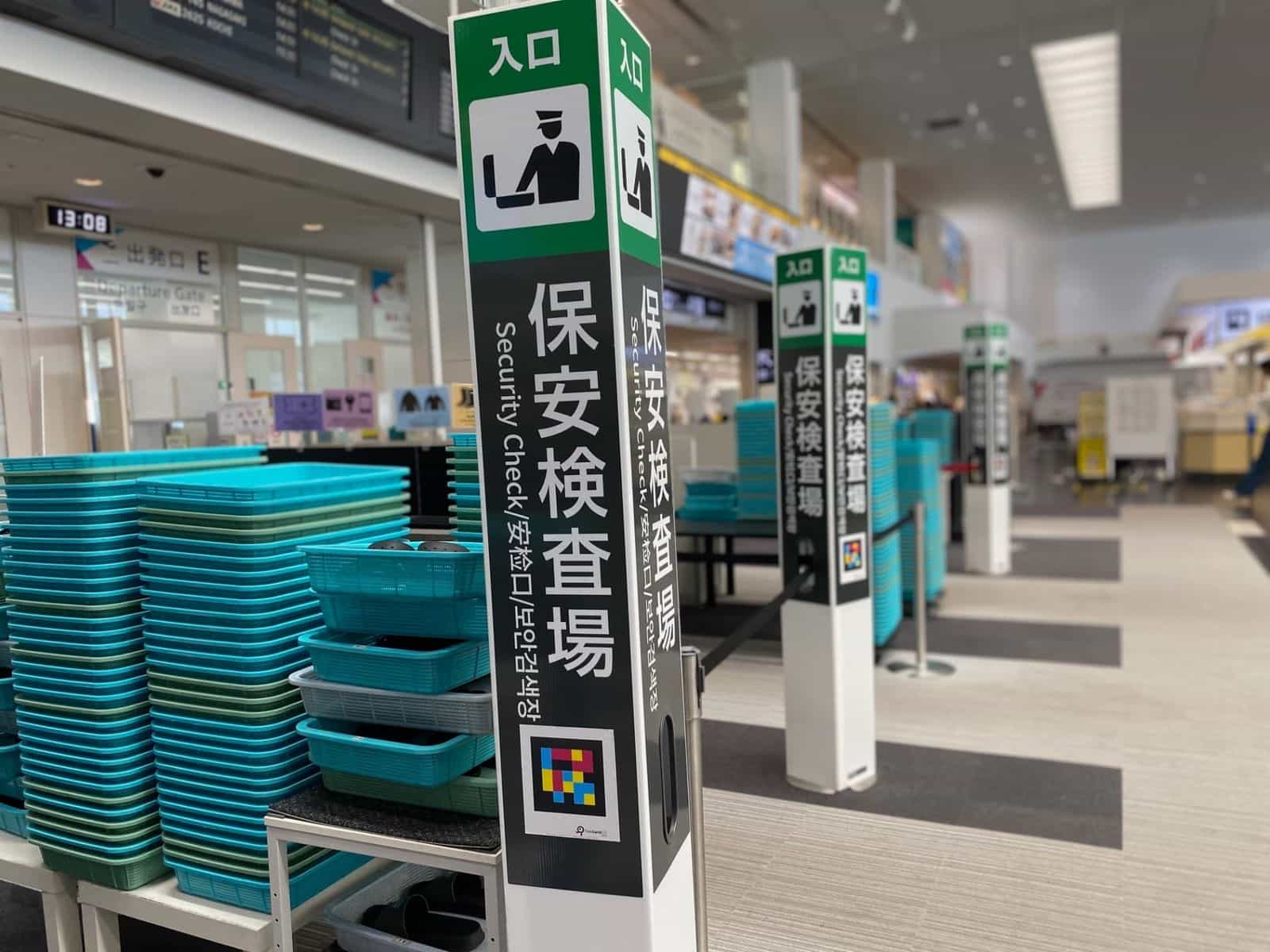 Drei weiß-grüne «Security Check»-Totems im Kobe Airport, jedes mit NaviLens-GO-Tag am Fuß