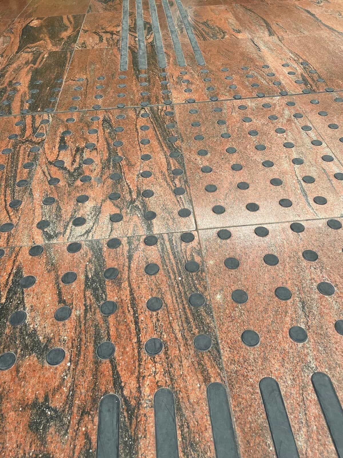 Detail des roten Granitbodens mit Adifs taktilem System in María Zambrano