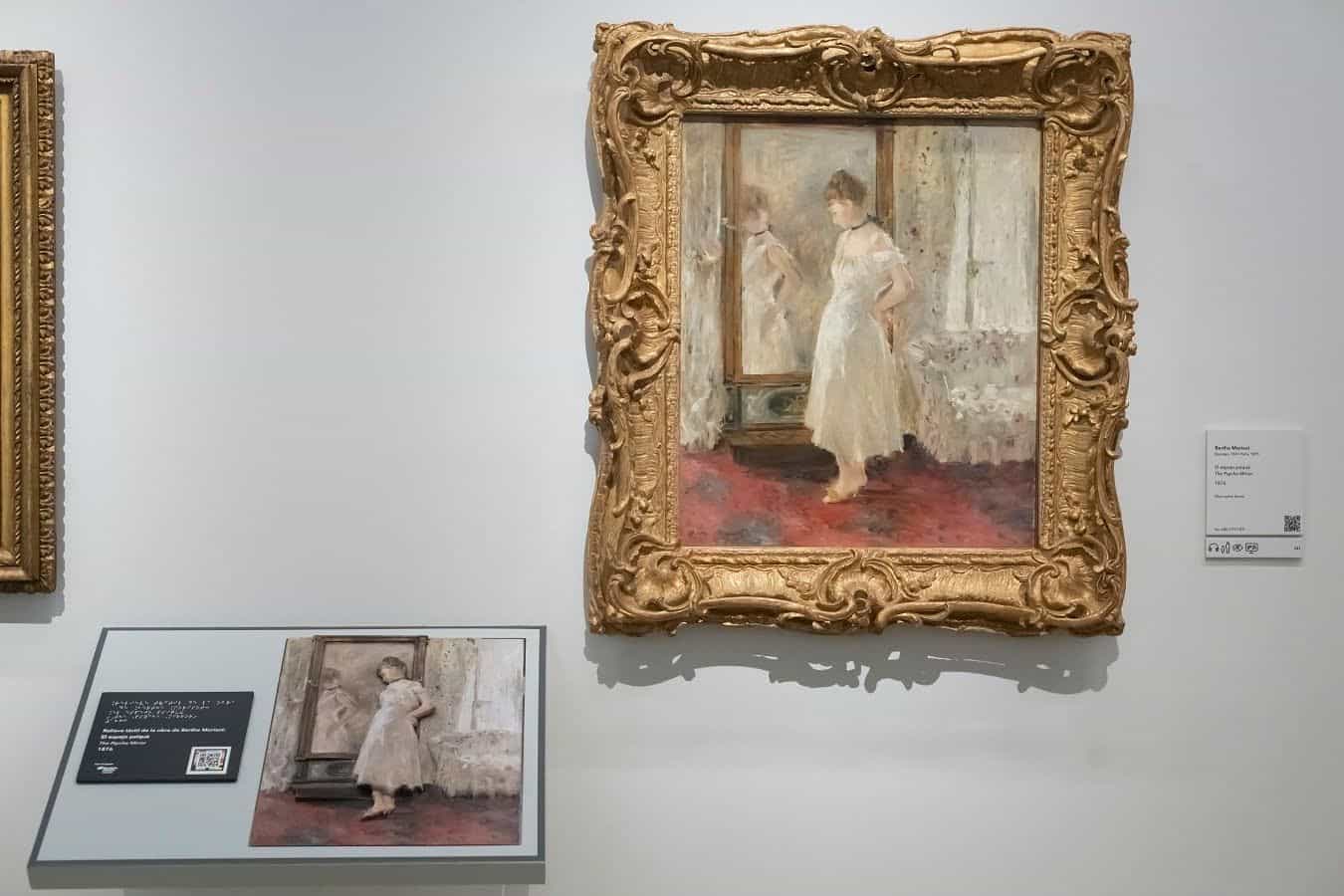 Relieve táctil y braille junto a la obra El espejo psiqué de Berthe Morisot en el Museo Thyssen-Bornemisza, con código NaviLens para acceder al contenido accesible.