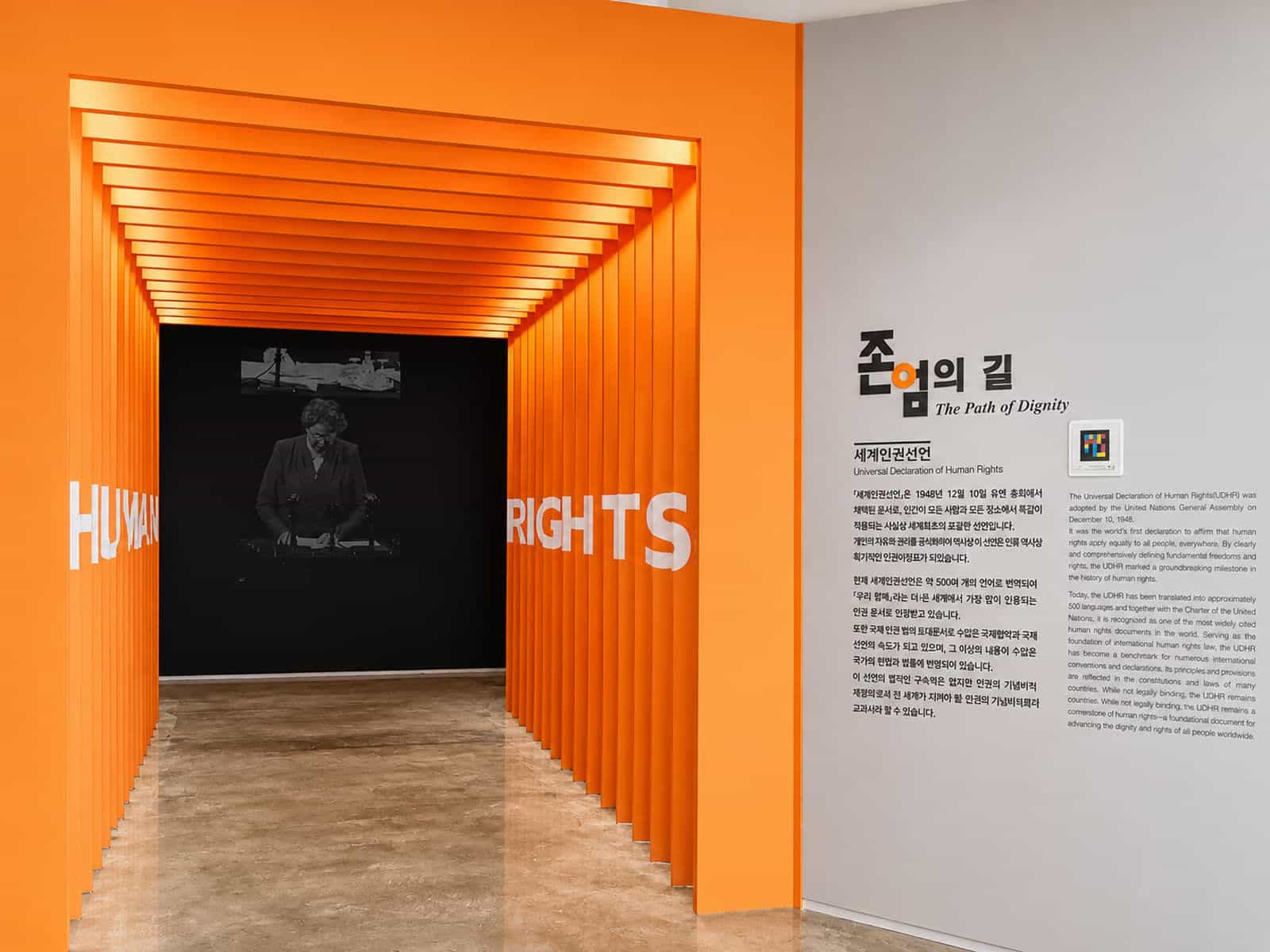 「尊厳の道」ゾーンのオレンジ色の「HUMAN RIGHTS」トンネル。韓国語と英語の世界人権宣言の本文と、パネル横のNaviLensコード