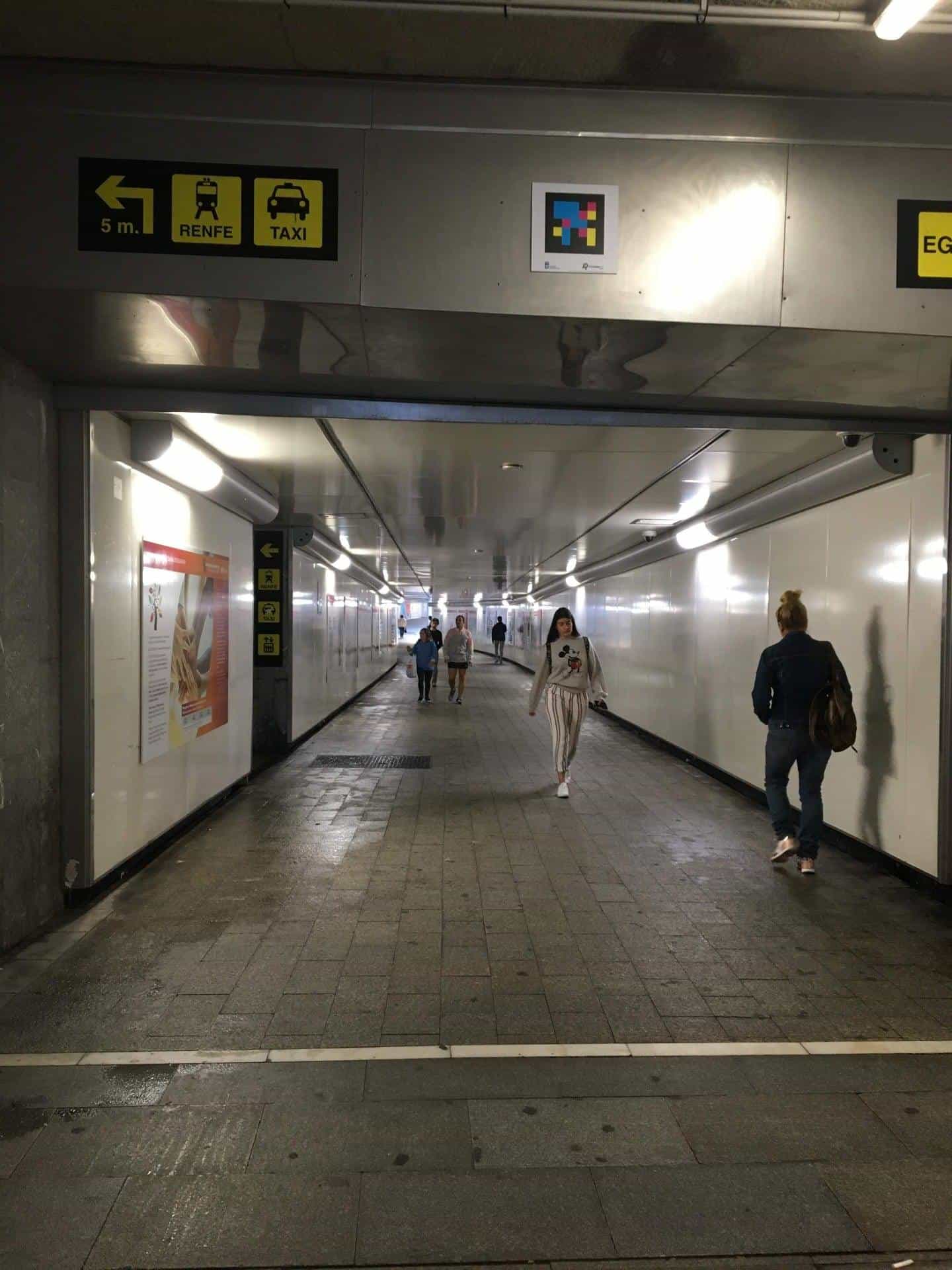 Connecting tunnel between the bus station and the train station, with a RENFE / TAXI sign and a NaviLens code