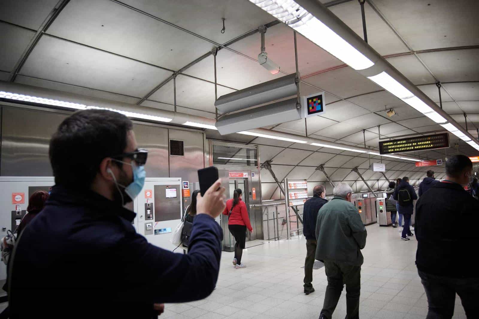 User pointing their phone at the NaviLens code in a Metro Bilbao concourse