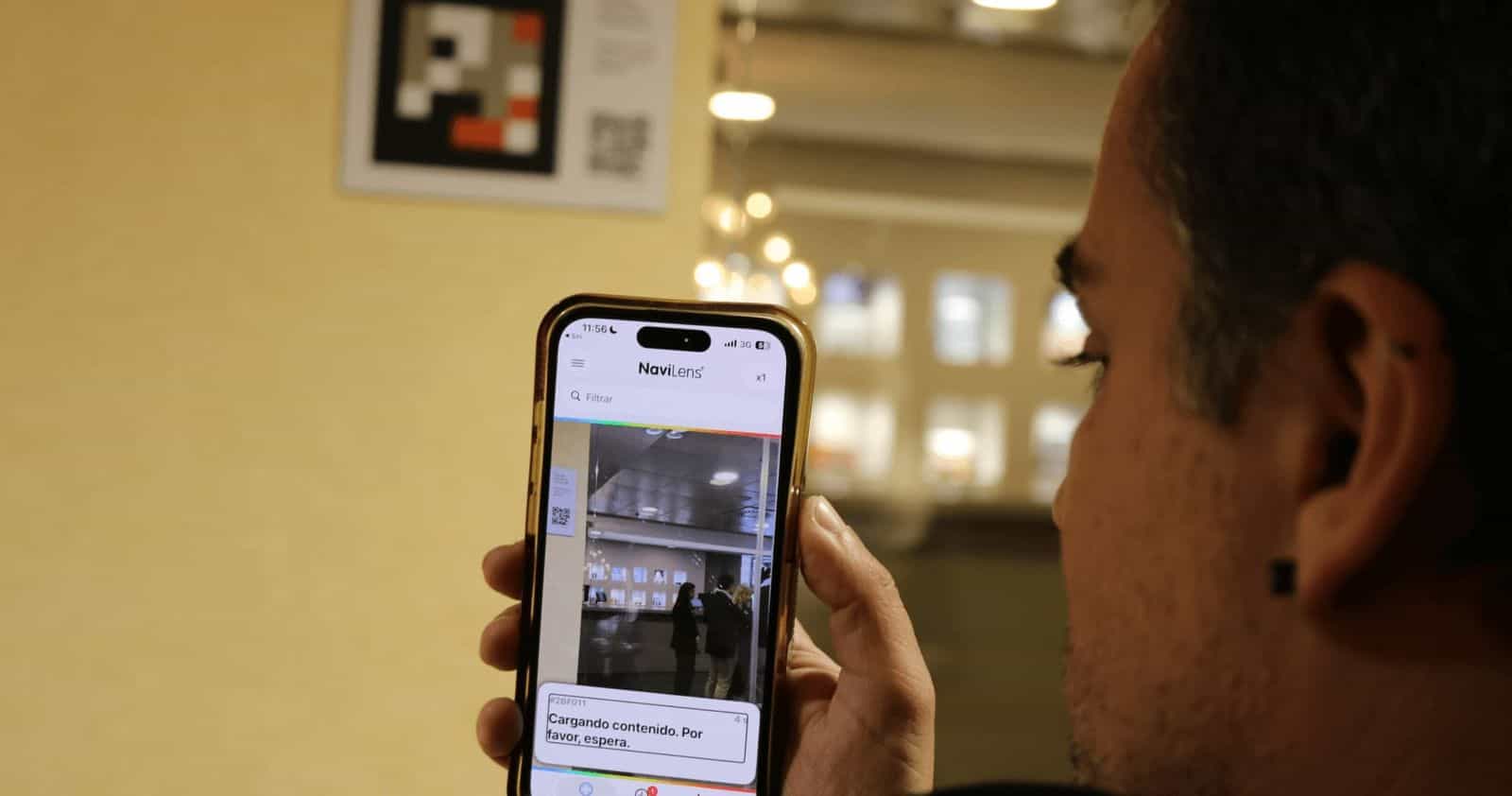 Ein Gast des AR Diamante Beach scannt mit der NaviLens-App auf seinem iPhone einen NaviLens-Code an der Hotelwand