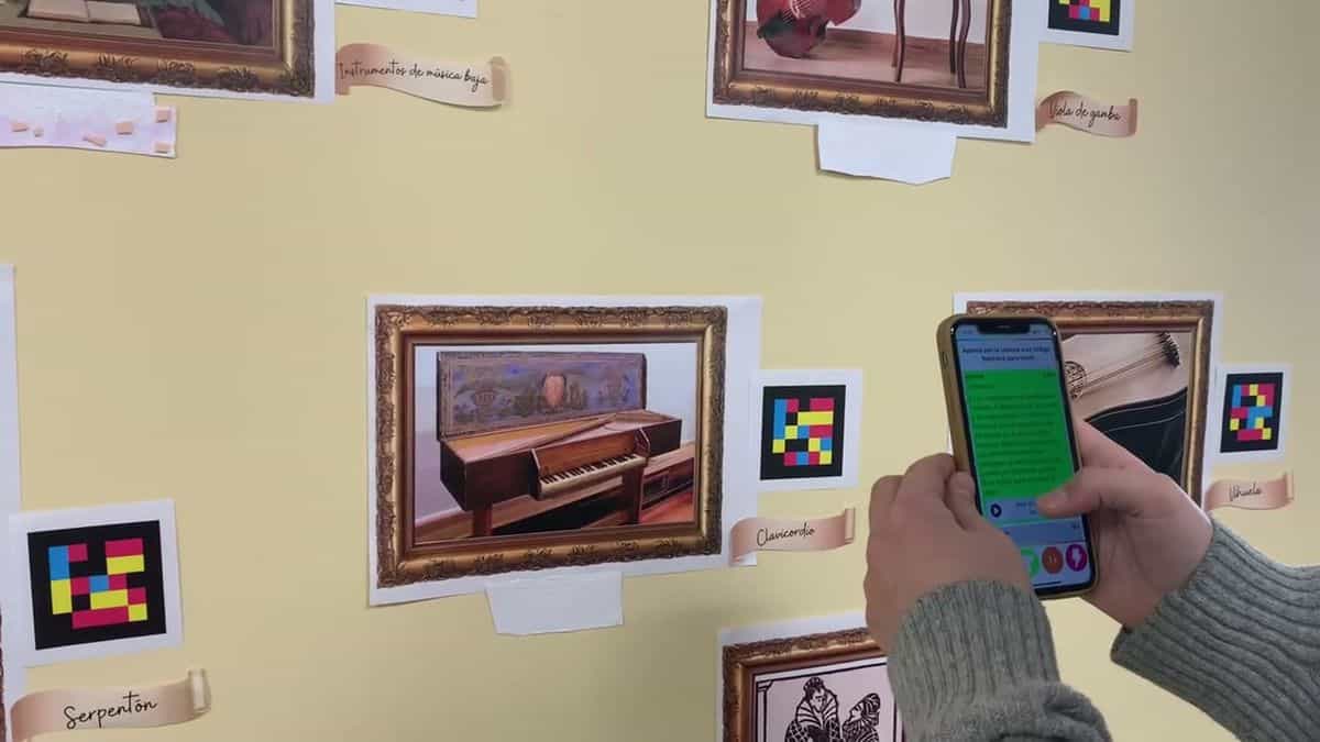 Lehrer liest mit einem iPhone den NaviLens-Code neben dem Clavichord-Gemälde im Museum für Musikinstrumente der Renaissance des IES Parque Goya vor