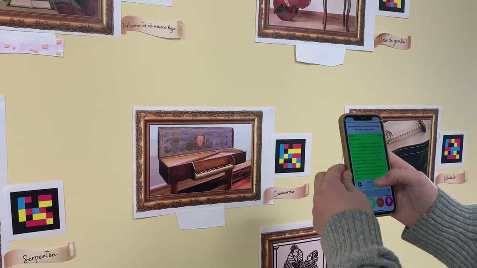 IESパルケ・ゴヤのルネサンス音楽博物館で、クラヴィコードの絵の隣にあるNaviLensコードをiPhoneで読み取っている教師