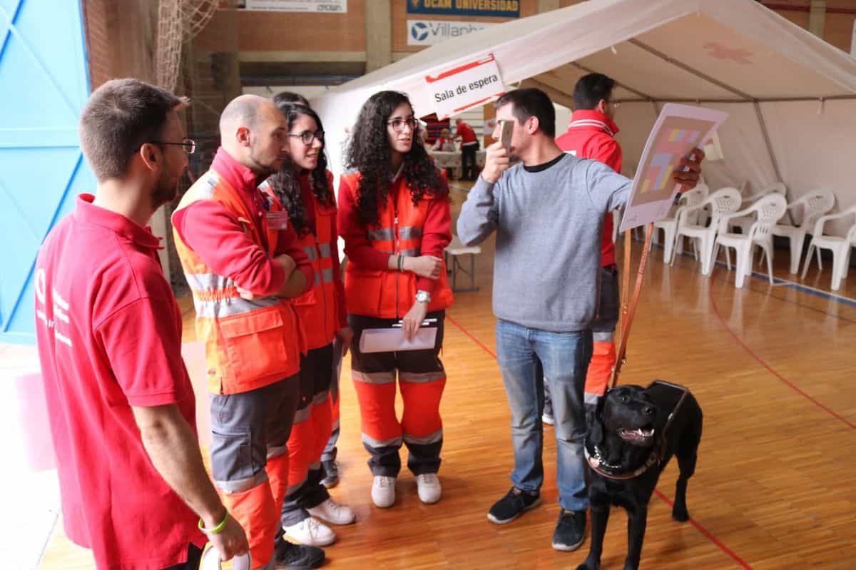 UME · Cruz Roja · Murcia 2018 — Blinde Person mit Blindenführhund scannt einen Code