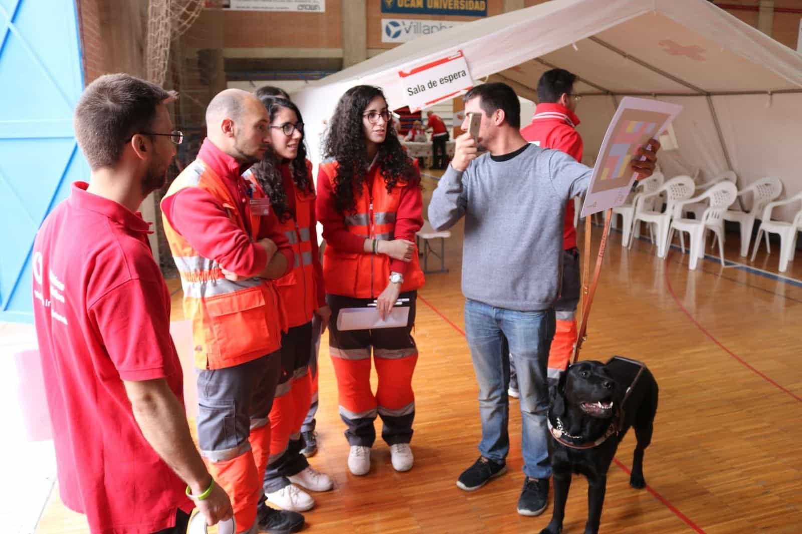 UME · Cruz Roja · Murcia 2018 — Blind person with a guide dog scanning a code