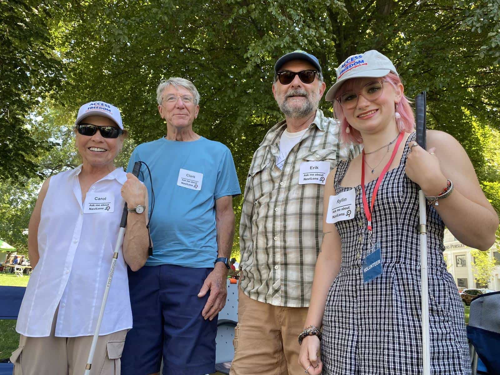 Four Hands Around the Capitol volunteers in “Access = Freedom” caps wearing name stickers that read “Ask me about NaviLens”; two of them hold white canes